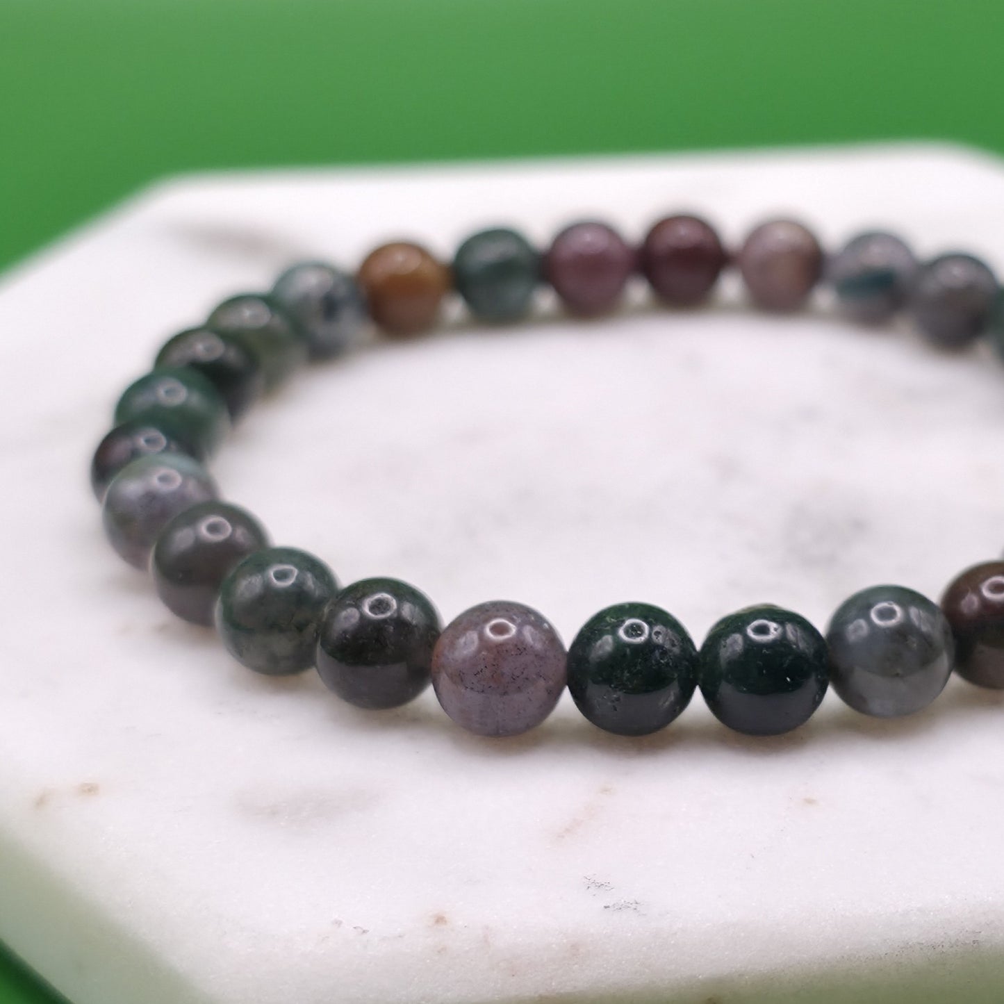 Handmade natural Indian Agate beaded bracelet, 6mm beads laying flat on a marble background.