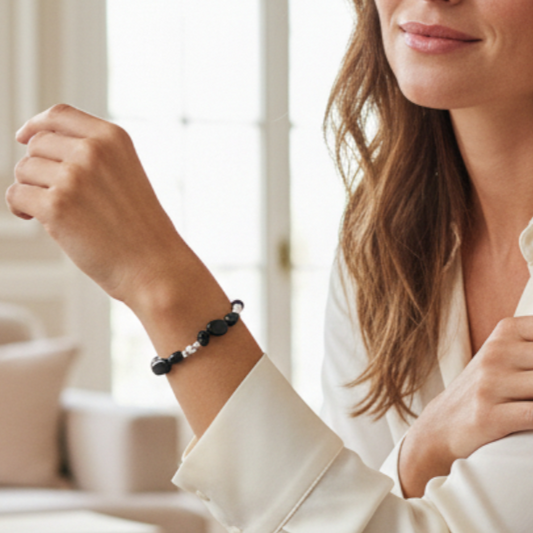A woman wearing a beaded bracelet with black and silver beads, shown in a bright indoor setting.