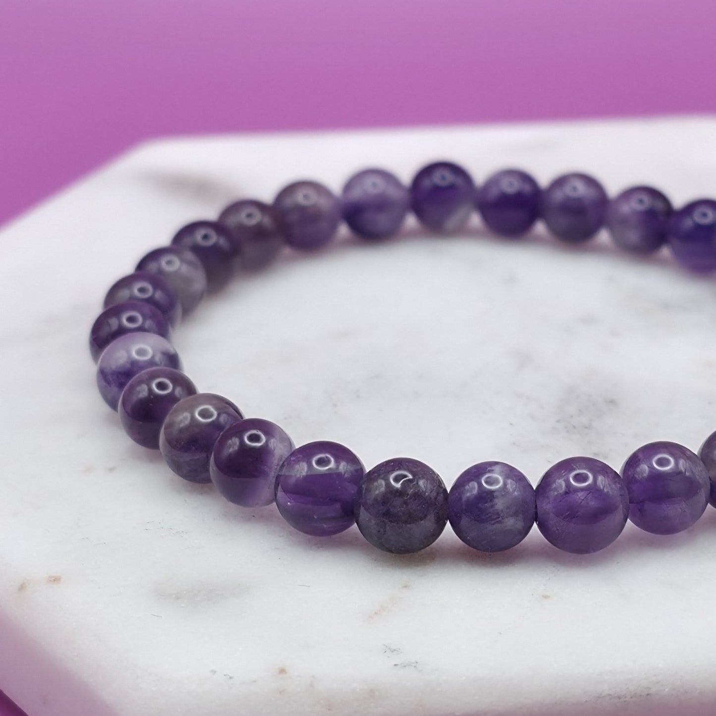 Handmade natural Amethyst beaded bracelet, 6mm beads laying flat on a marble plate.