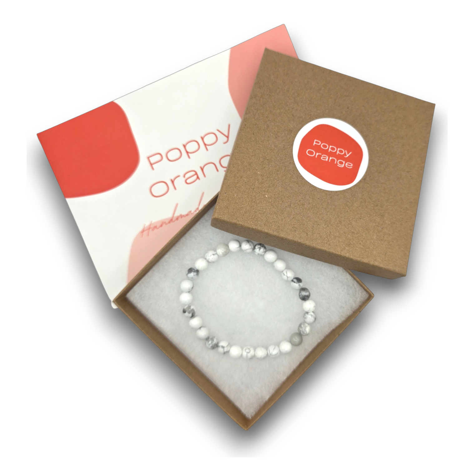 A beaded bracelet with white and gray beads displayed inside an open kraft gift box with a white insert. The box lid is shown beside it, featuring a red circular sticker that reads 'Poppy Orange' and the words 'Handmade' on the inner lid.