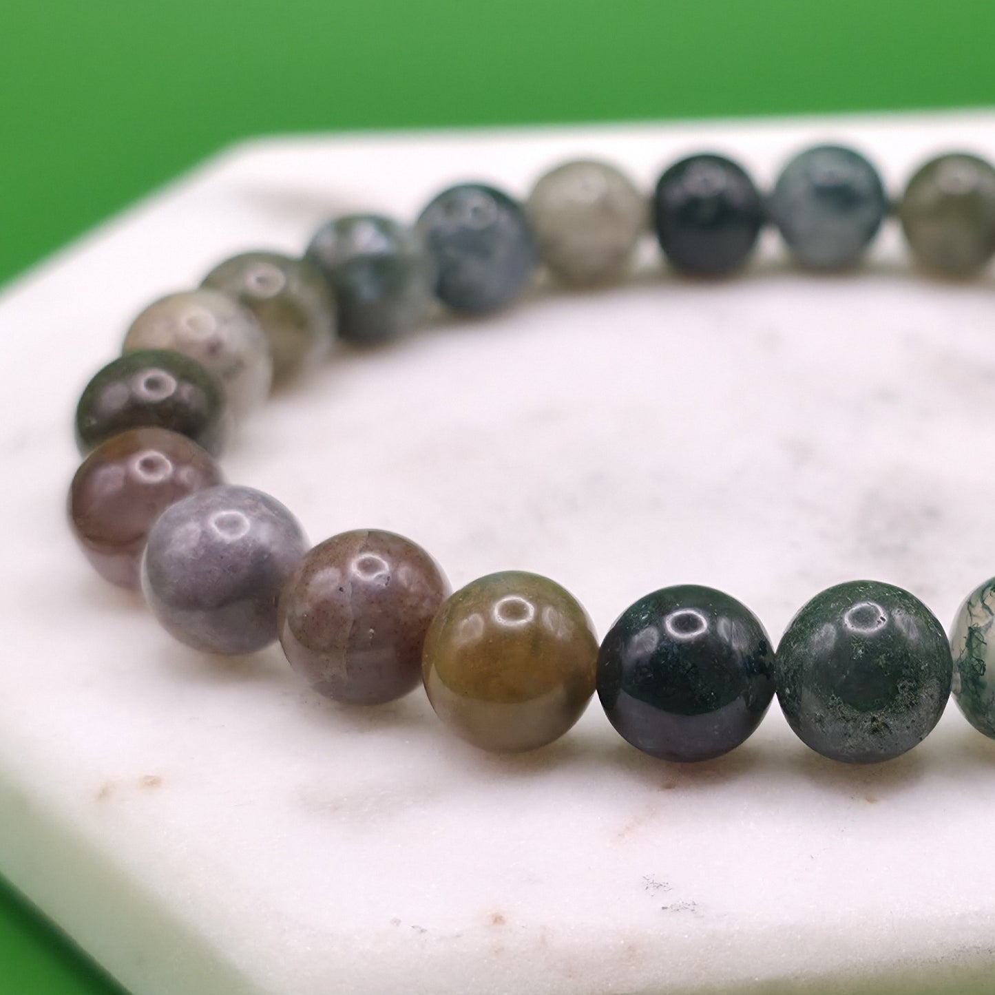 Handmade natural Indian Agate beaded bracelet, 8mm beads laying flat on a marble plate.