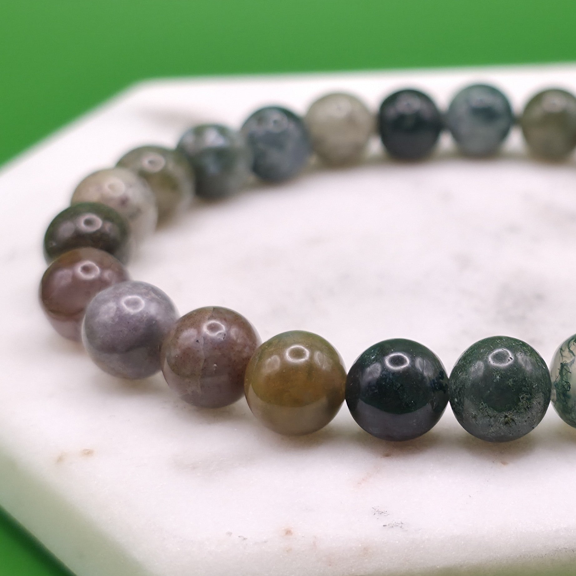 Handmade natural Indian Agate beaded bracelet, 8mm beads laying flat on a marble plate.