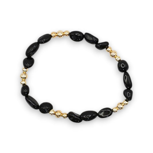 A beaded stretch bracelet featuring polished black onyx nugget beads and small metallic gold spacer beads, displayed on a clean white background.