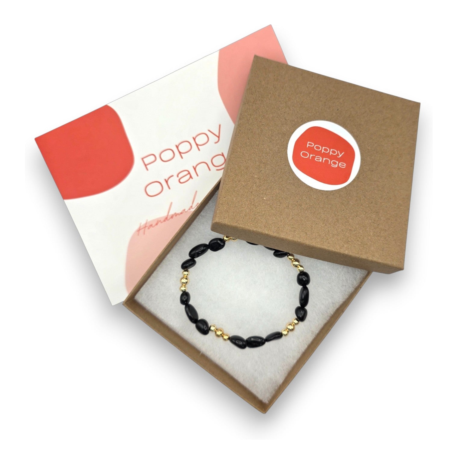 A beaded bracelet with black onyx and gold beads presented in an open kraft gift box with a white insert. The box lid has a round red and white Poppy Orange logo sticker, and the inner card reads 'Poppy Orange Handmade'.