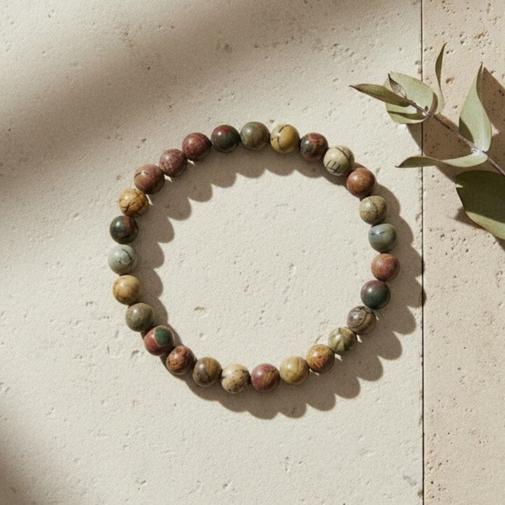Handmade natural Red Creek Jasper beaded bracelet, 6mm beads on a pale stone background.