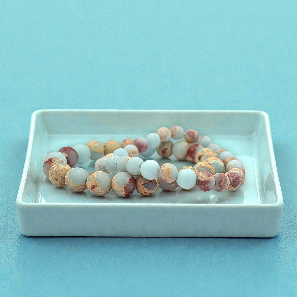 Beaded bracelet on a white dish with a light blue background