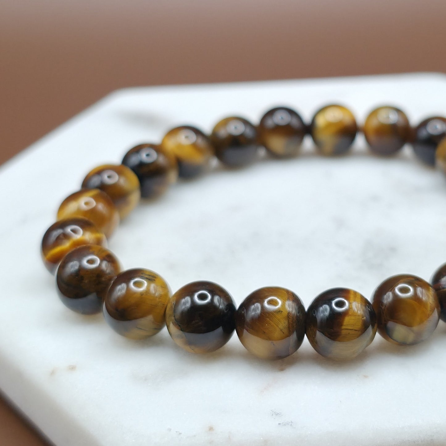 Handmade natural Tiger Eye beaded bracelet, 8mm beads laying flat on a marble plate.