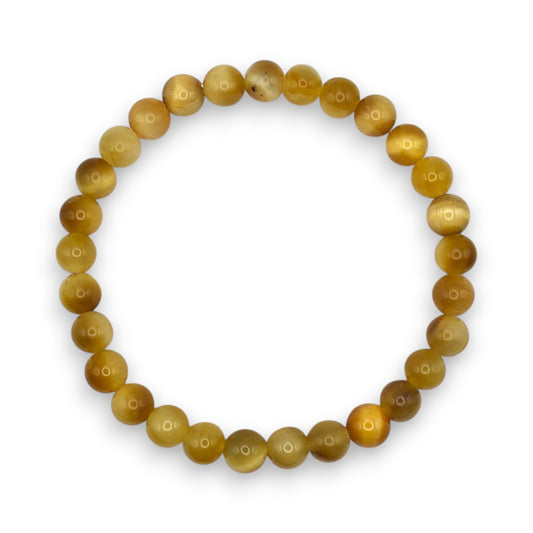 A beaded stretch bracelet made of round, polished golden-yellow beads with natural variations in tone, arranged in a circular shape on a white background.