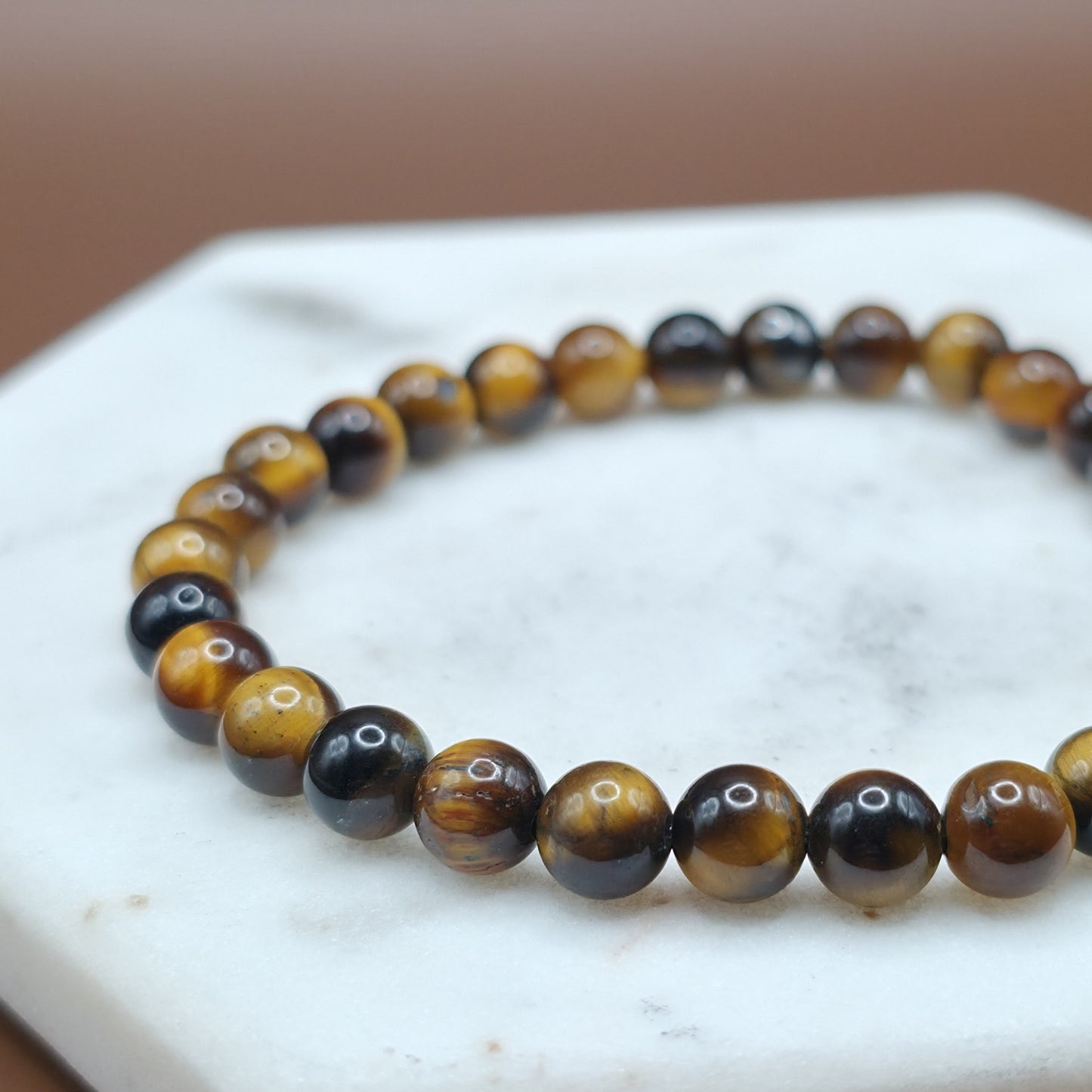 Handmade natural Tiger Eye beaded bracelet, 6mm beads laying flat on a marble plate.