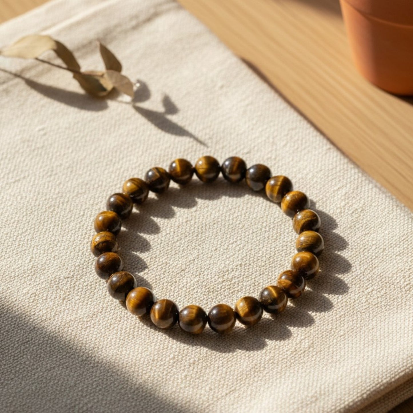 Handmade natural Tiger Eye beaded bracelet, 8mm beads laying flat on beige linen on wood.